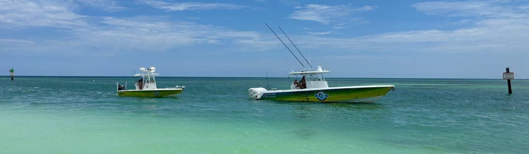Two fishing charters wade near the shore of Islamadora, FL. The sea is calm, clear, and a tealish blue.