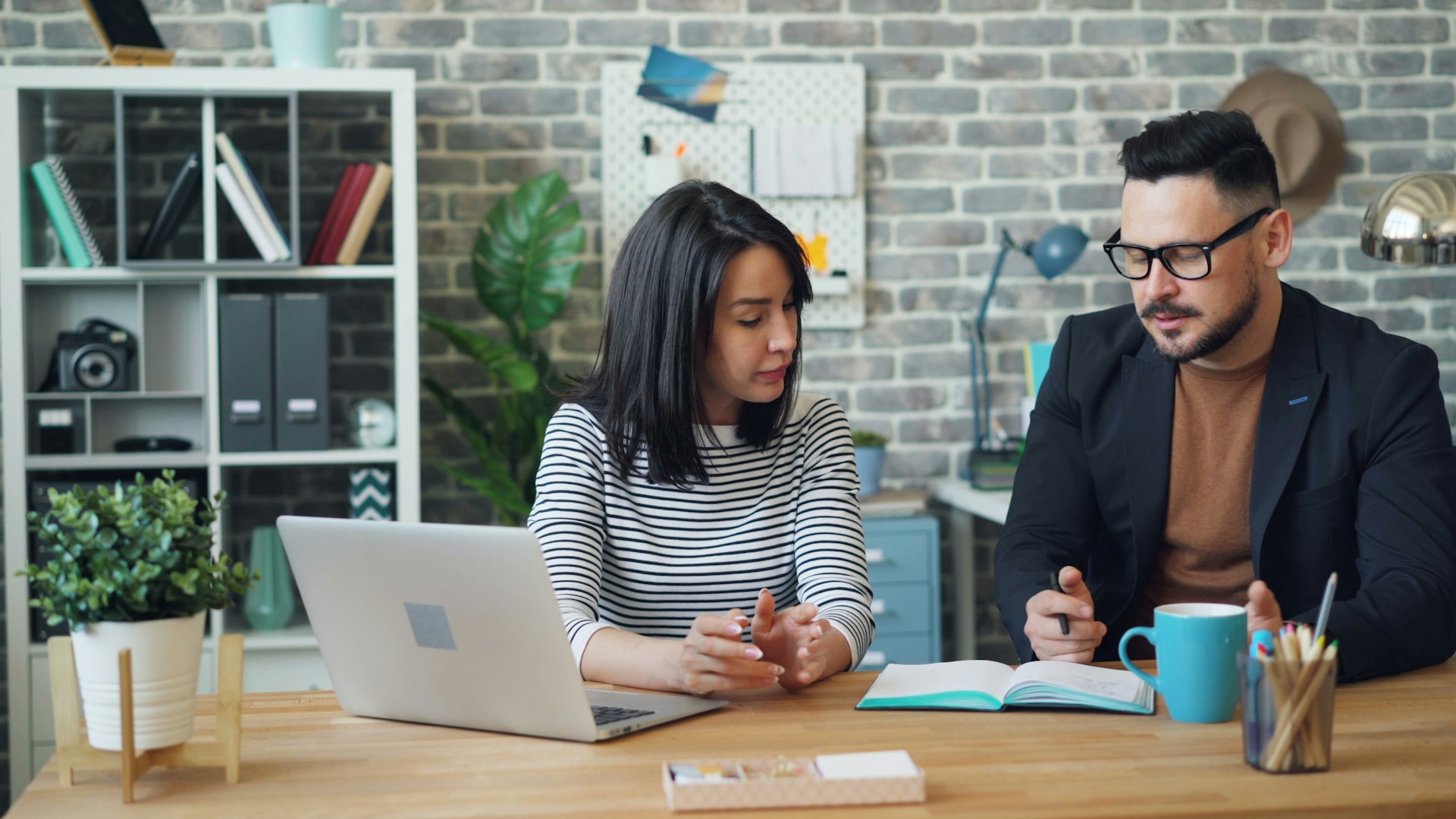 Two colleagues in a focused one-on-one conversation at an office desk