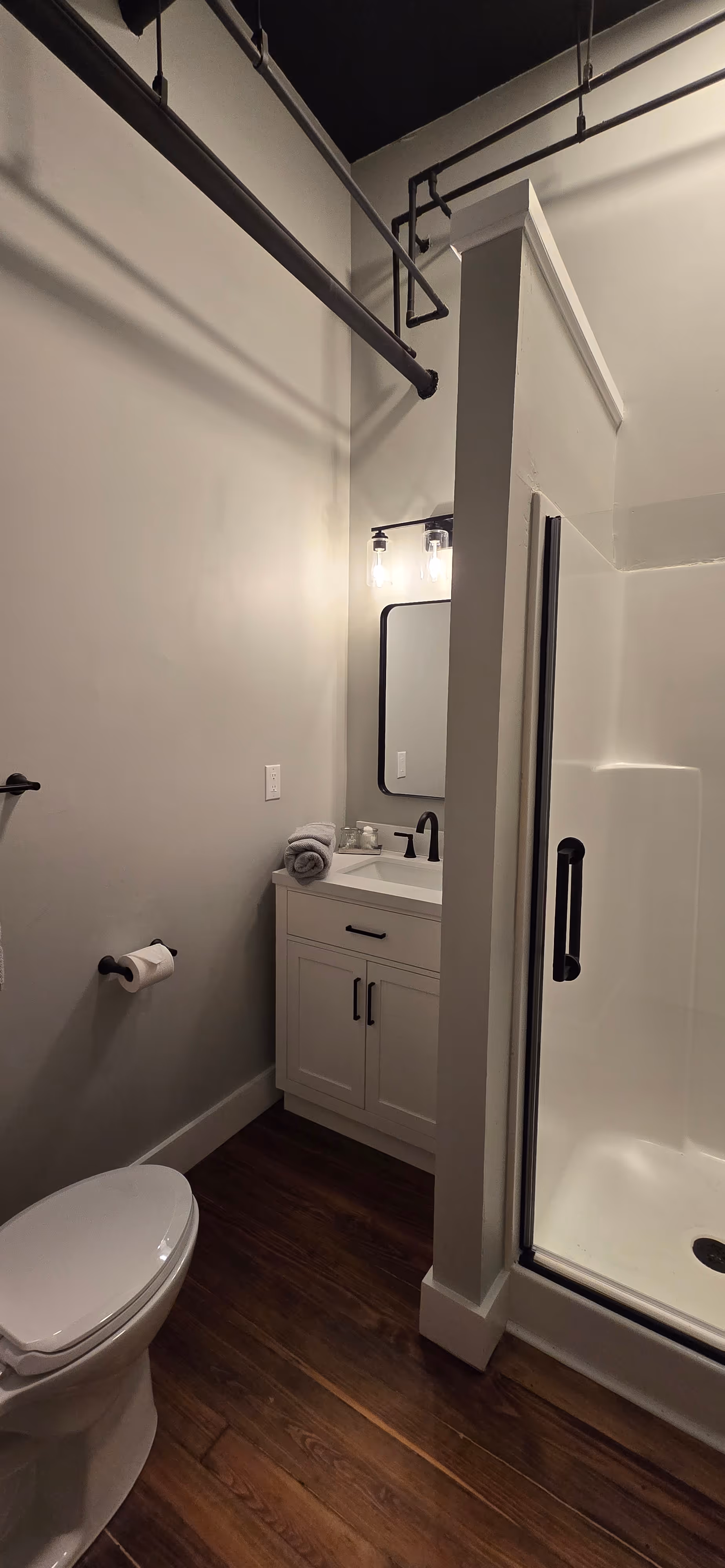 Cozy bedroom with exposed brick walls, wooden furniture, king-size bed with white and blue floral bedding, two windows, and bedside lamps.