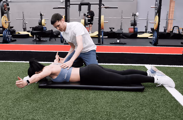 Physical therapist assisting patient on exercise mat in a Vancouver physiotherapy clinic.