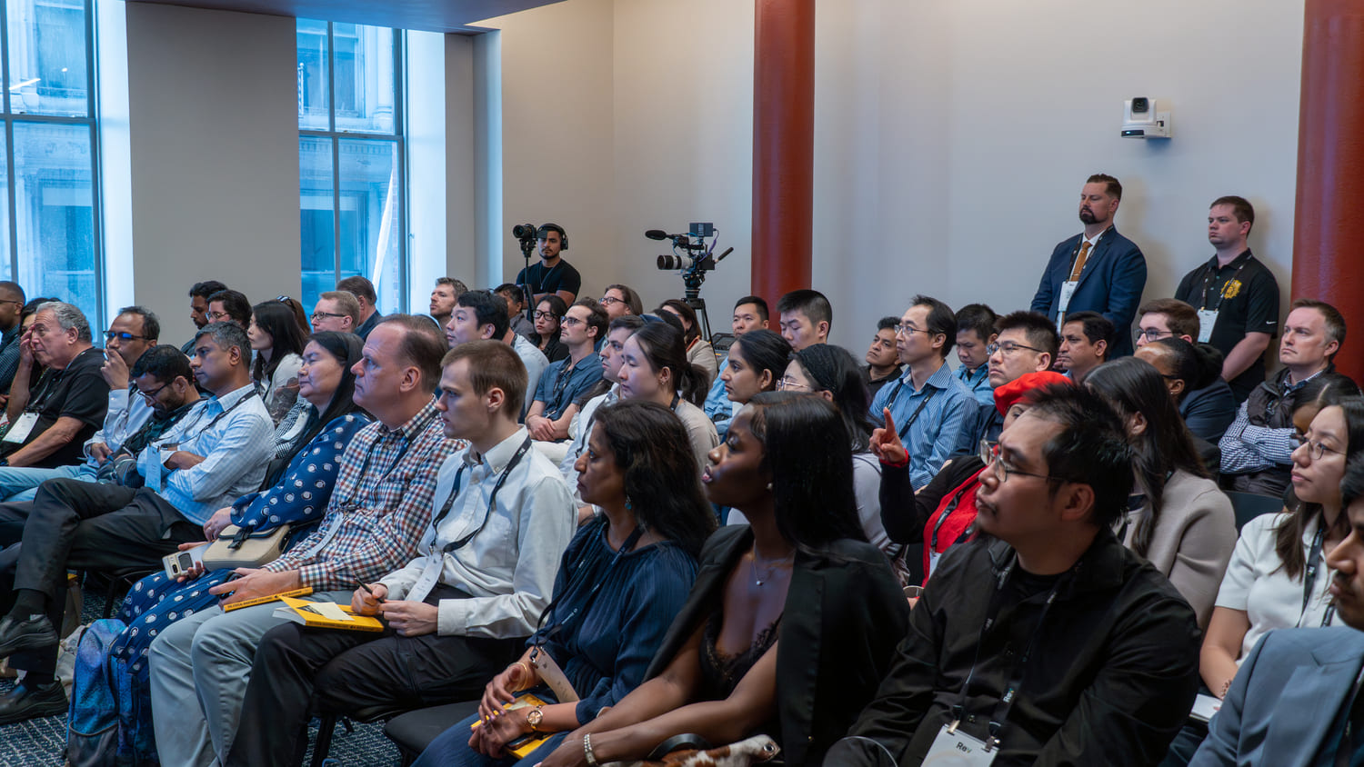 A diverse group of people seated in a conference room attentively listening to a speaker.
