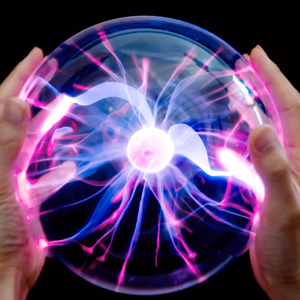 Hands holding a glowing plasma ball with pink and blue electric streams inside against a black background.