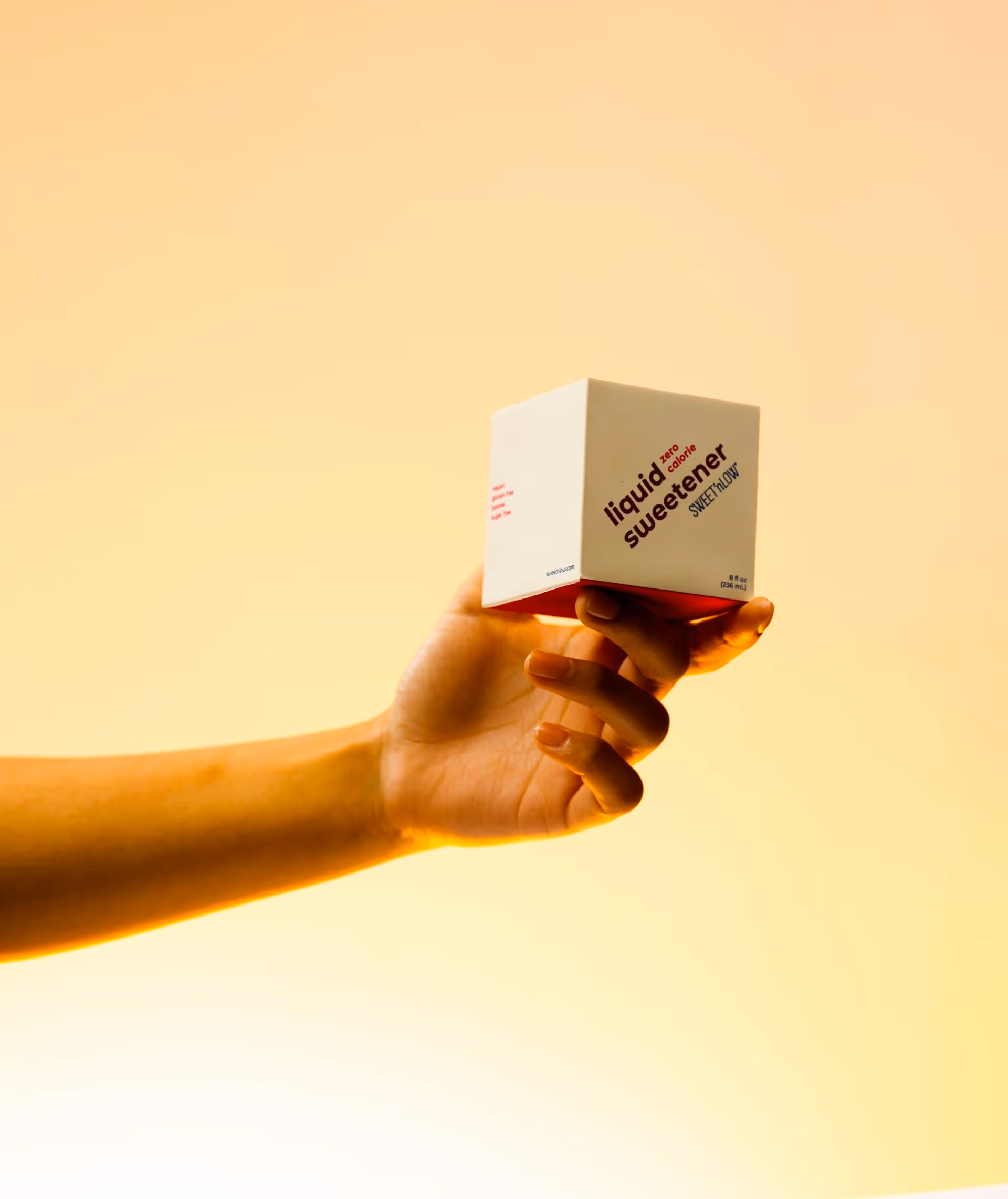 A photo of a hand holding a bottle of sweetener.