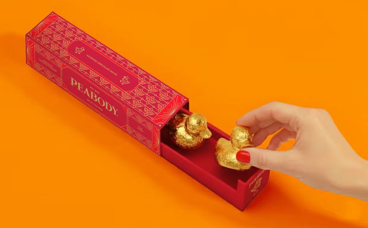 An AI-generated photo of chocolate duck packaging. A hand is grabbing one of them to take it out.