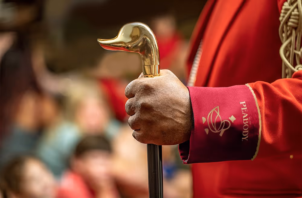 A person wearing a red suit holding a duck-shaped cane in their hand.