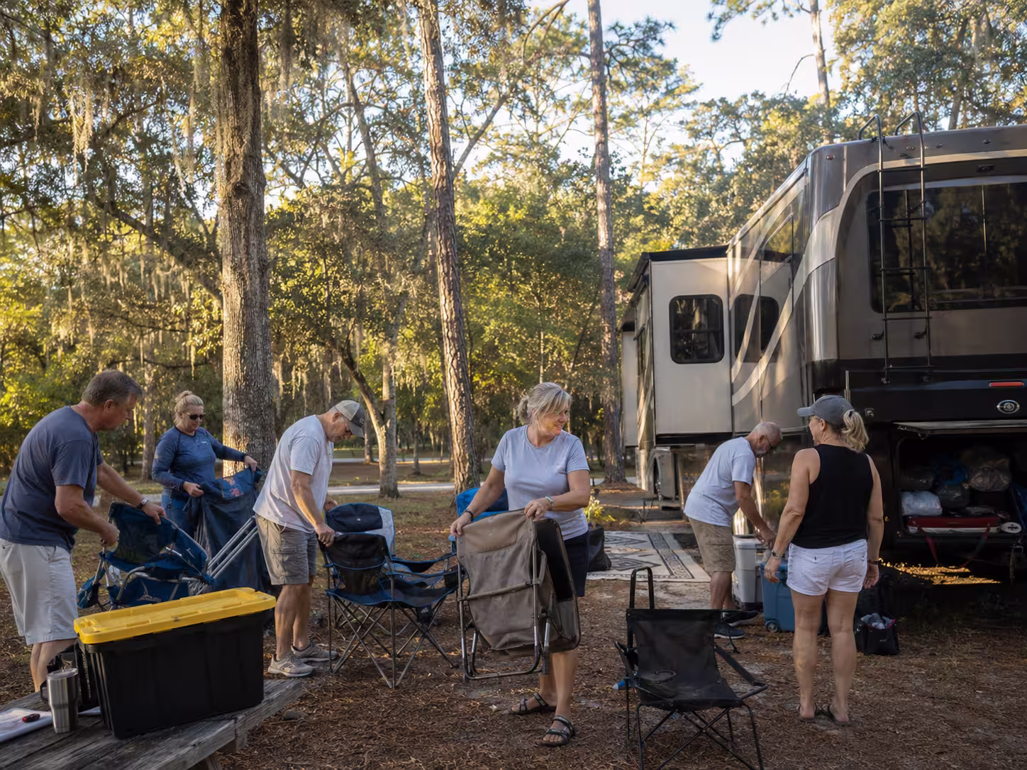 Group unloading gear beside a large RV at a Brooksville campground