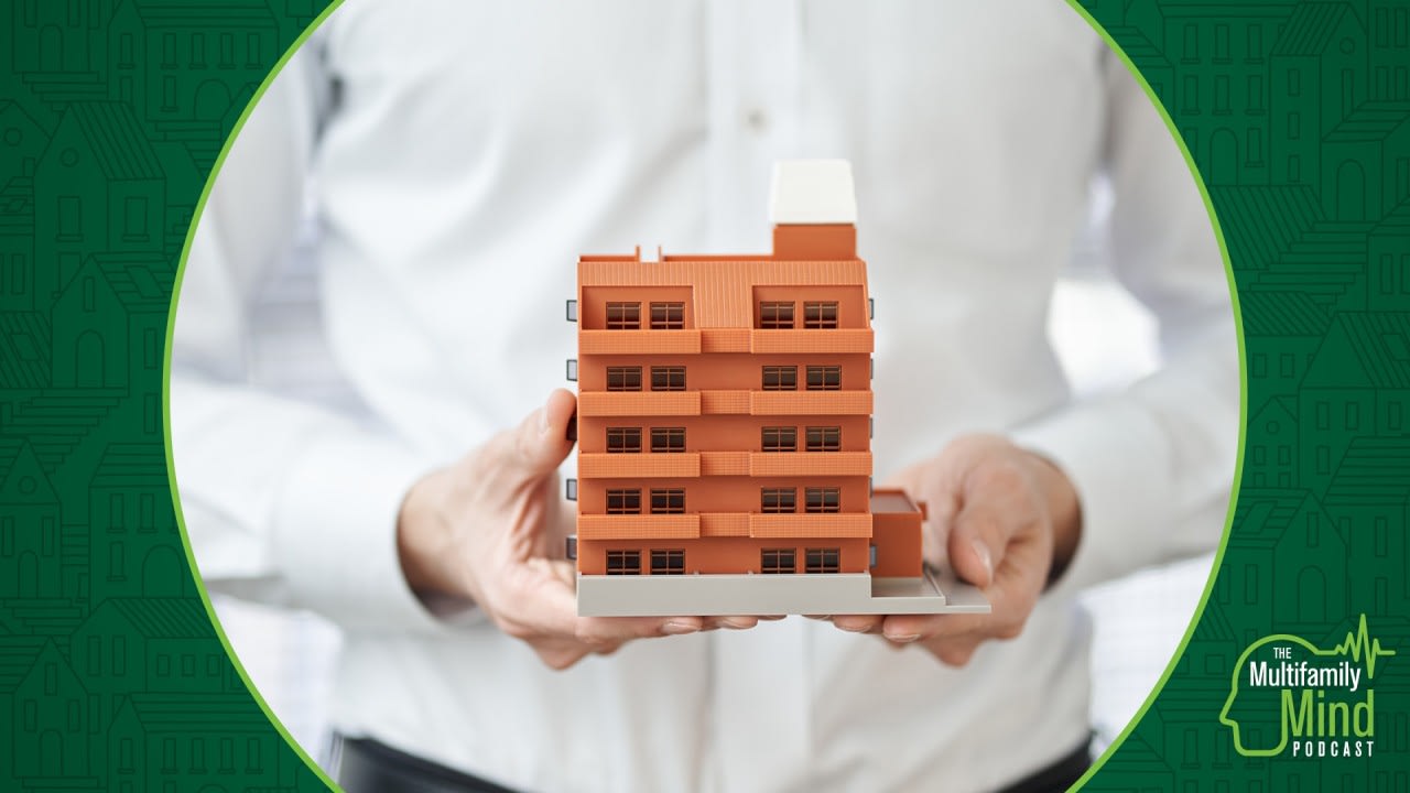 man holding an orange model of an apartment building