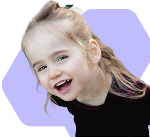 Smiling young girl with light brown hair tied back, wearing a dark top, against a purple background.