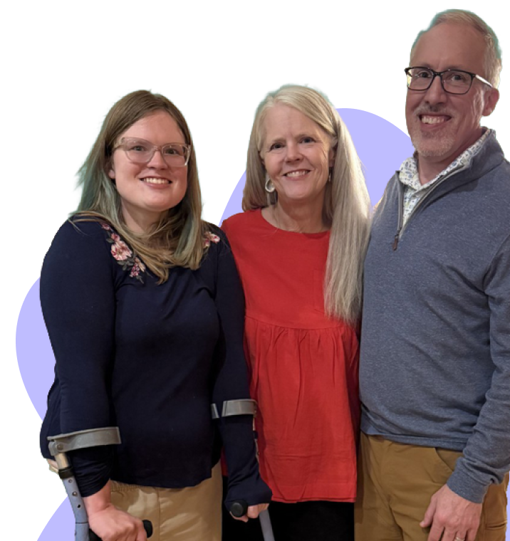 Smiling woman with crutches, woman in red blouse, and man in glasses posing together.