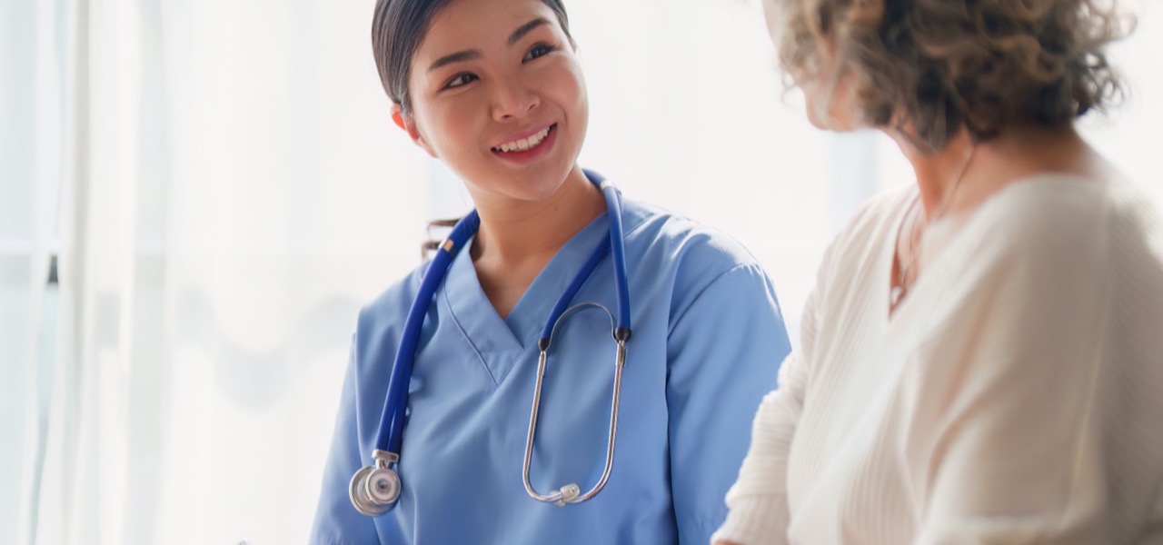 A nurse in blue scrubs talking with a patient