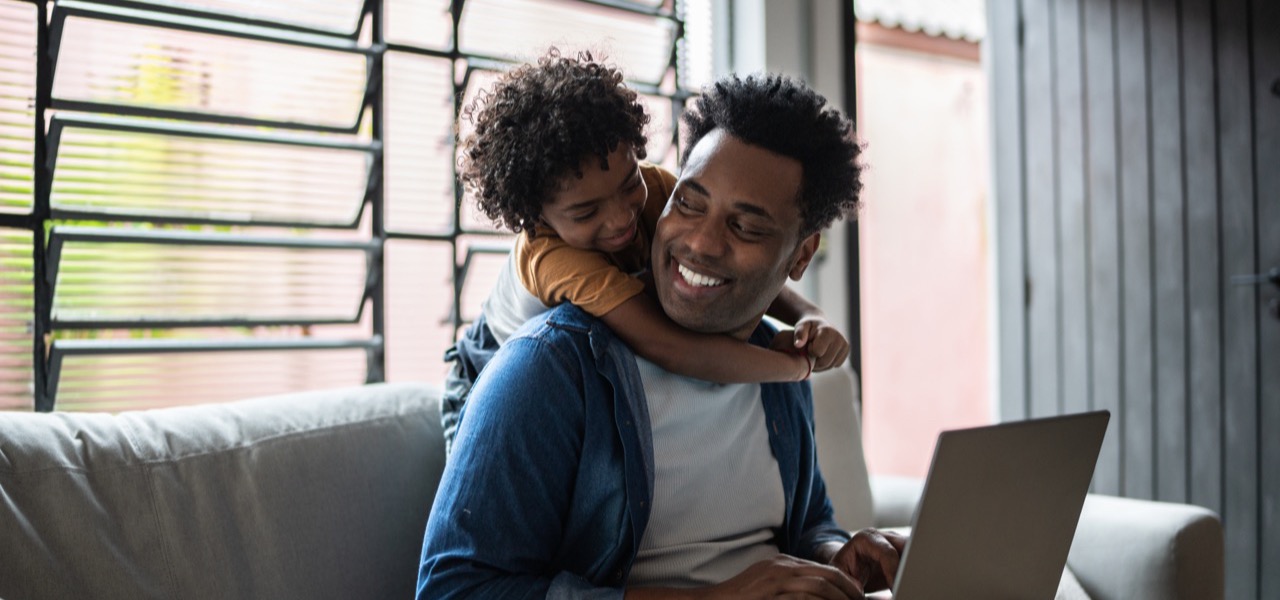 A father and his young child looking at a laptop together at home