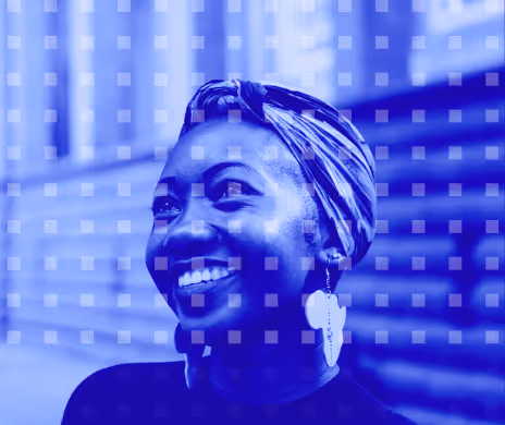 Smiling woman with headscarf and large earrings looking left with blurred outdoor steps background.