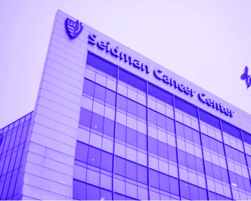 Modern multi-story hospital building with glass windows and Seton Cancer Center signage.