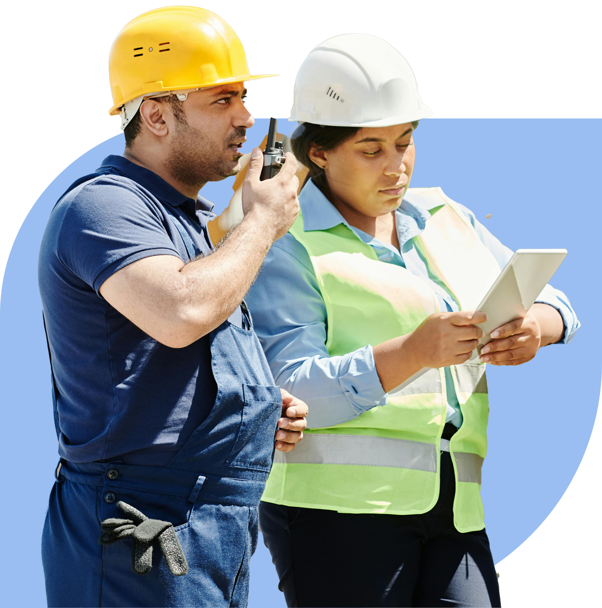 Dos trabajadores industriales, una mujer con casco blanco y chaleco reflectante, junto a un hombre con casco amarillo y overol azul, la mujer revisa un portapapeles; mientras el hombre habla mediante un walkie-talkie.