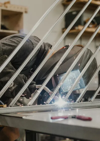 Welder leaning into work on angled metal project