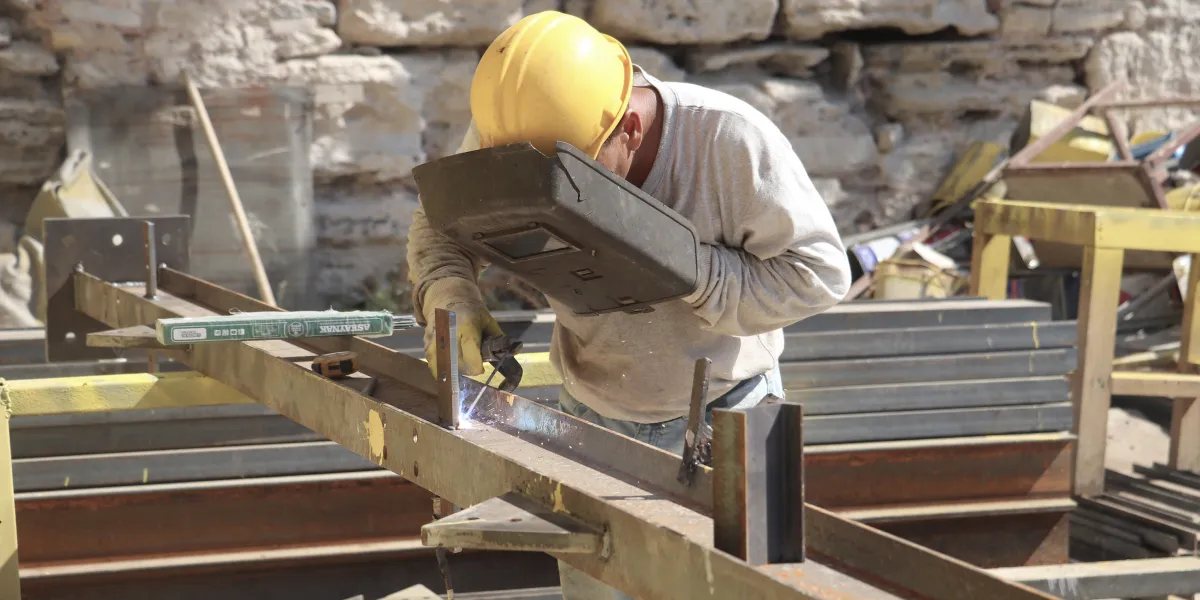 Welder holding hood while working