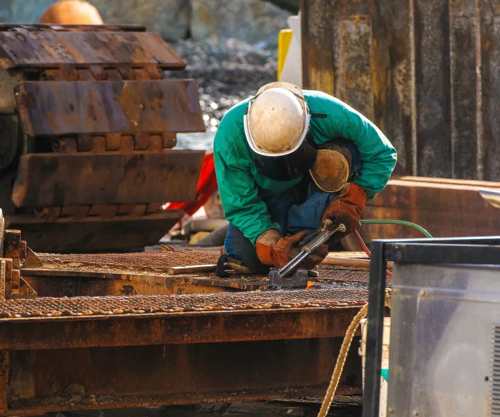 Welder outside kneeling while working