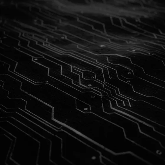 Close-up of a dark circuit board with illuminated lines and connection points.