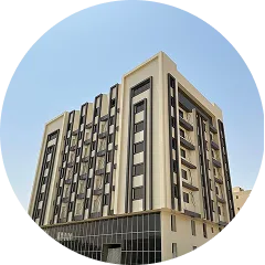 Modern multi-story beige building with large windows under a clear blue sky.