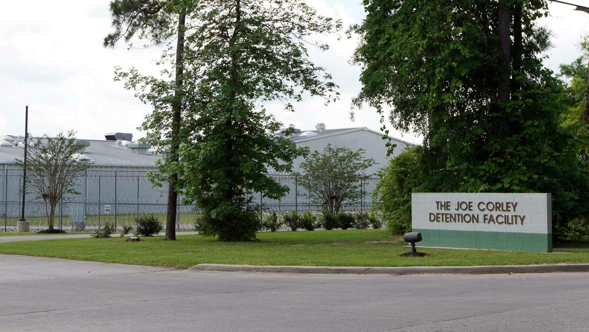 Edificio de detención llamado The Joe Corley Detention Facility rodeado de árboles y una cerca de alambre de púas. https://www.yourconroenews.com/neighborhood/moco/news/article/Mayor-No-need-for-new-immigration-detention-11076005.php 