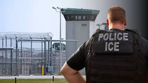 Oficial de policía ICE de espaldas observando una torre de vigilancia en una instalación de detención cercada. Source: https://www.univision.com/local/austin-kakw/nueva-ley-sb-8-texas-obliga-sheriffs-colaborar-ice-como-afecta-inmigrantes