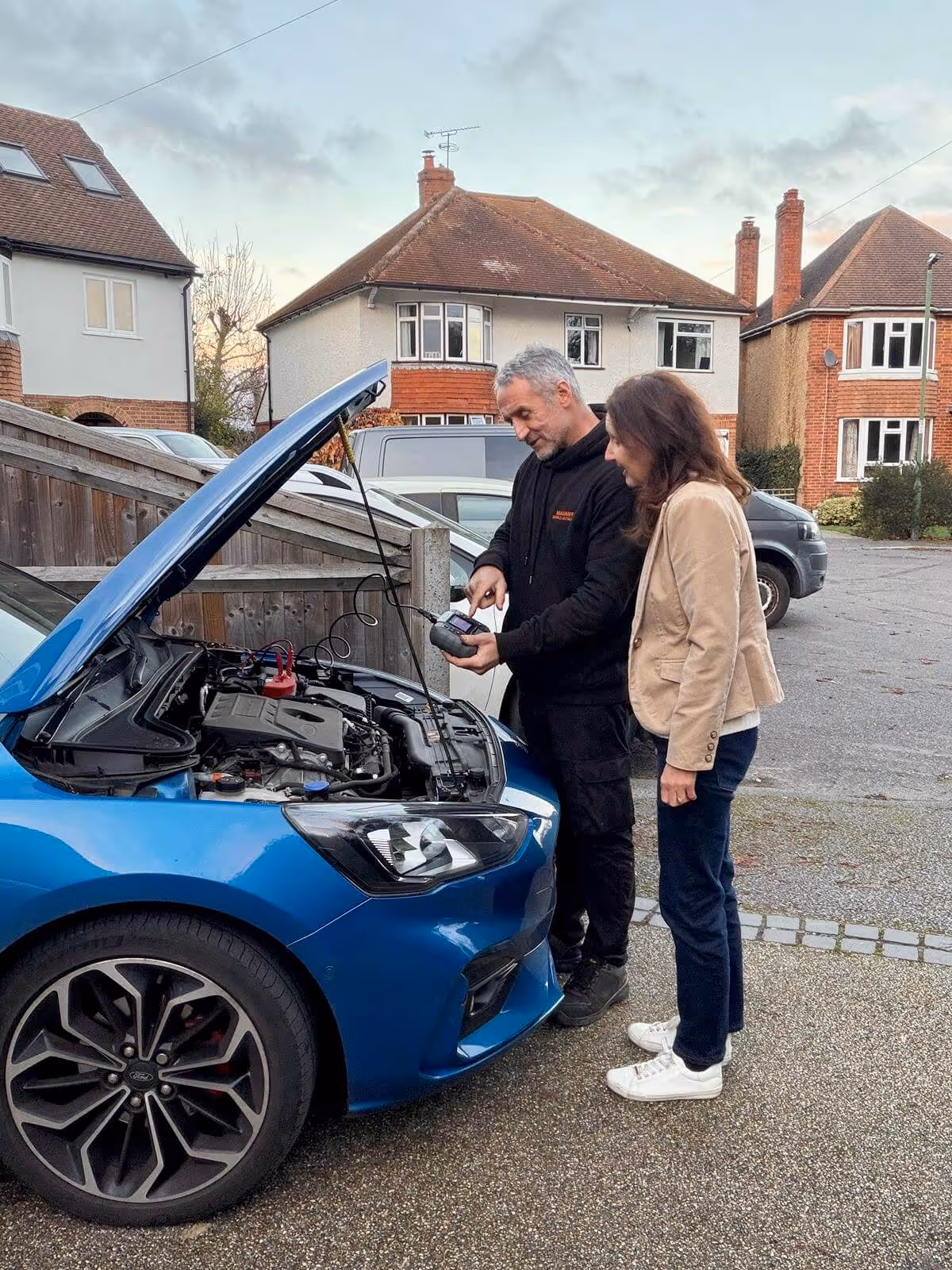 Mobile mechanic explaining pre-purchase inspection findings to a customer at a vehicle in Slough