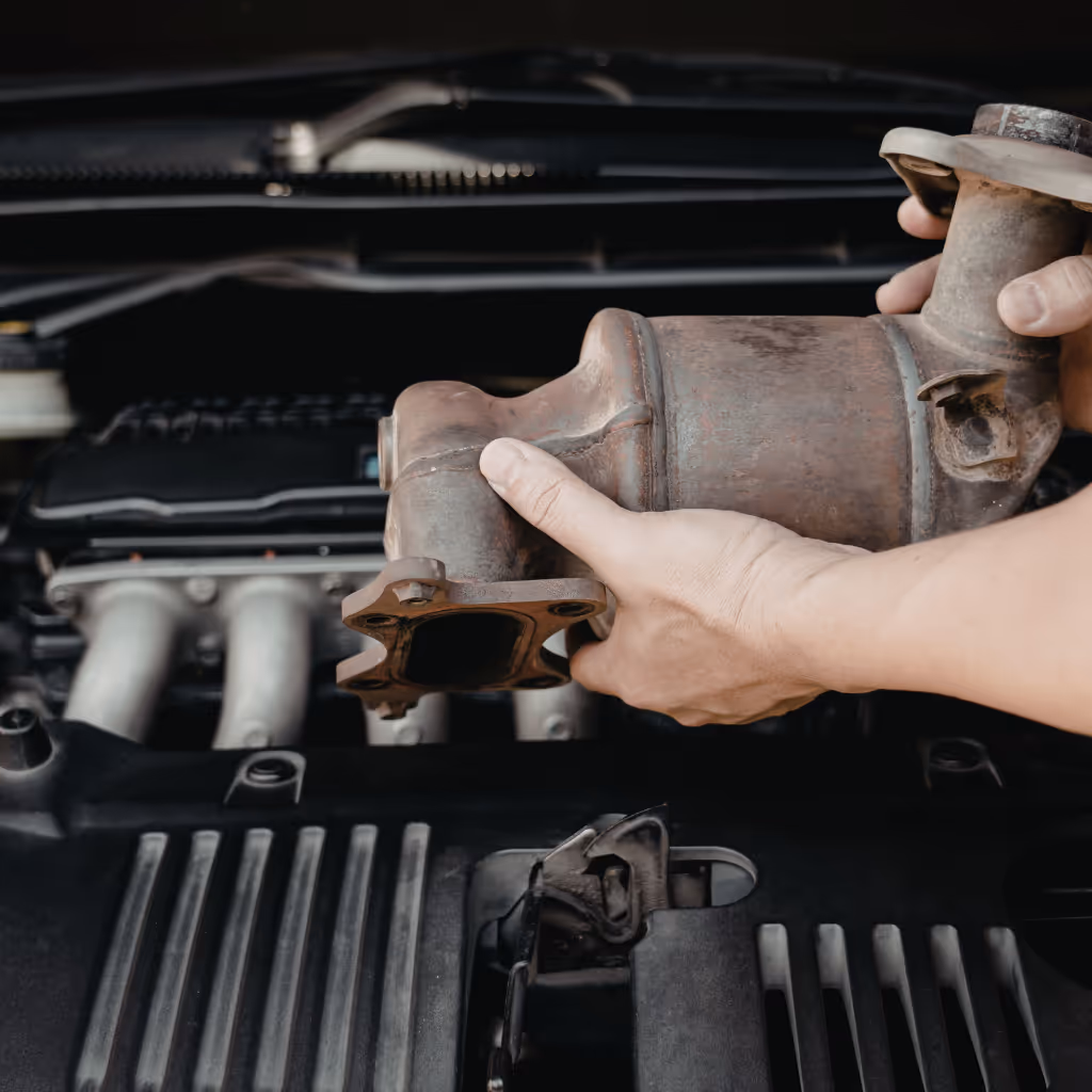 A Maxamy Mobile Autocare mechanic inspecting a catalytic converter during an on-site service. We provide expert replacement of exhaust components and DPF systems to ensure your vehicle passes emissions standards.