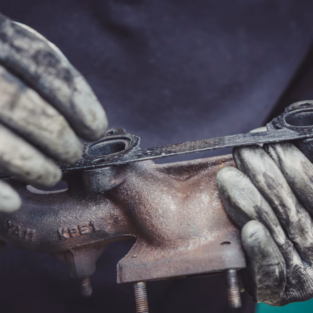 Precision fitting of a new exhaust manifold gasket. We repair blowing exhausts, fix dangerous fume leaks, and replace worn gaskets to restore your engine's performance and safety.