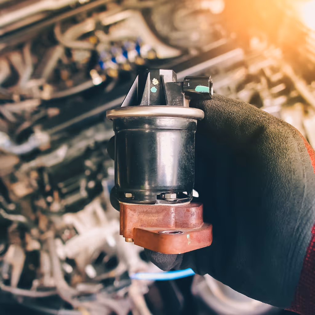 Close-up of a faulty EGR valve being removed. Maxamy Mobile Autocare specializes in diagnosing engine warning lights and replacing emission control components like EGR valves at your home or workplace.