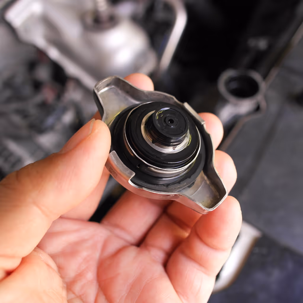 Inspecting a radiator cap for seal integrity. A faulty cap can lead to overheating; Maxamy Mobile Autocare checks all cooling system components to prevent breakdowns.