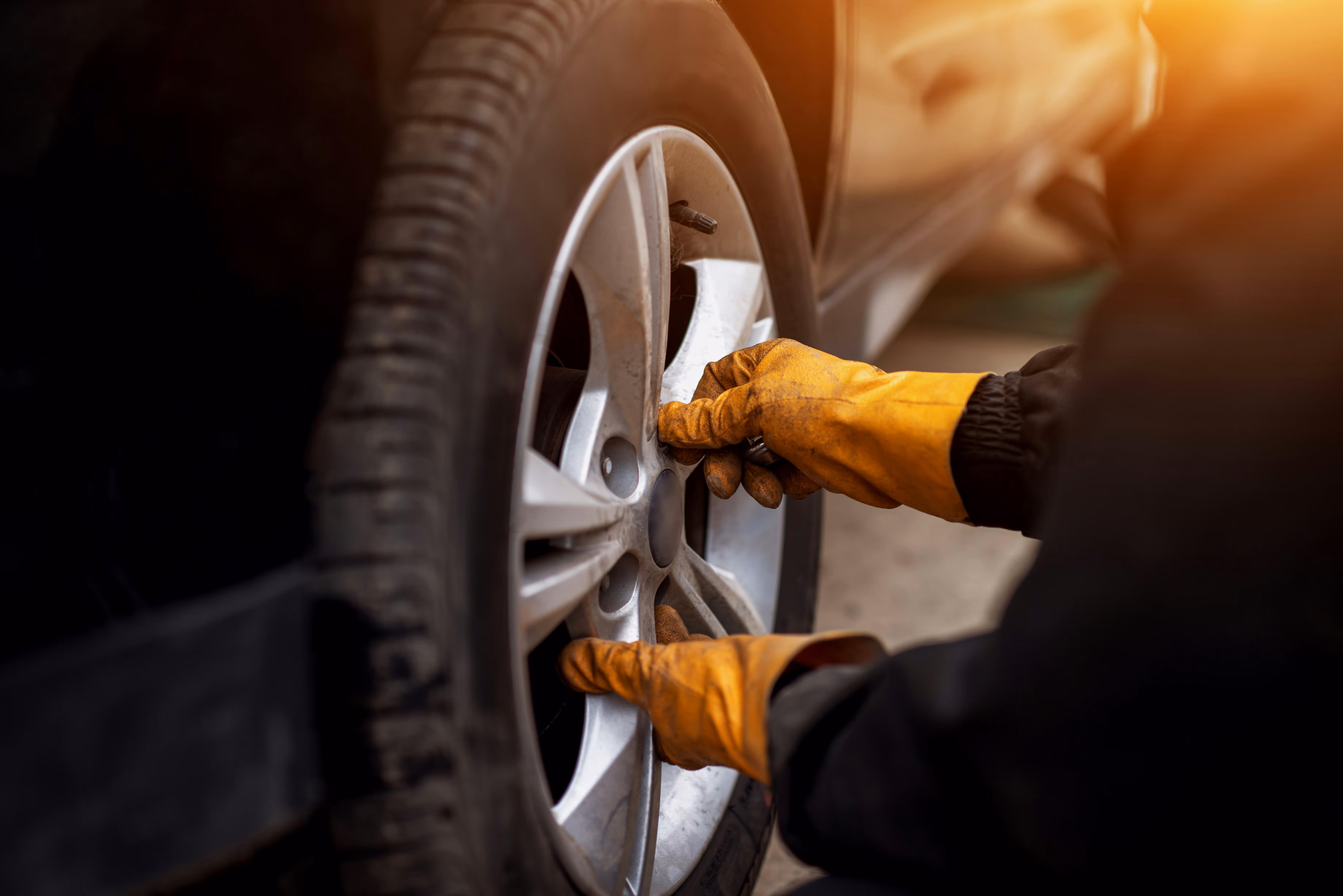 Close-up of a mobile mechanic carrying out hands-on car repair work on a vehicle wheel at a customer’s location