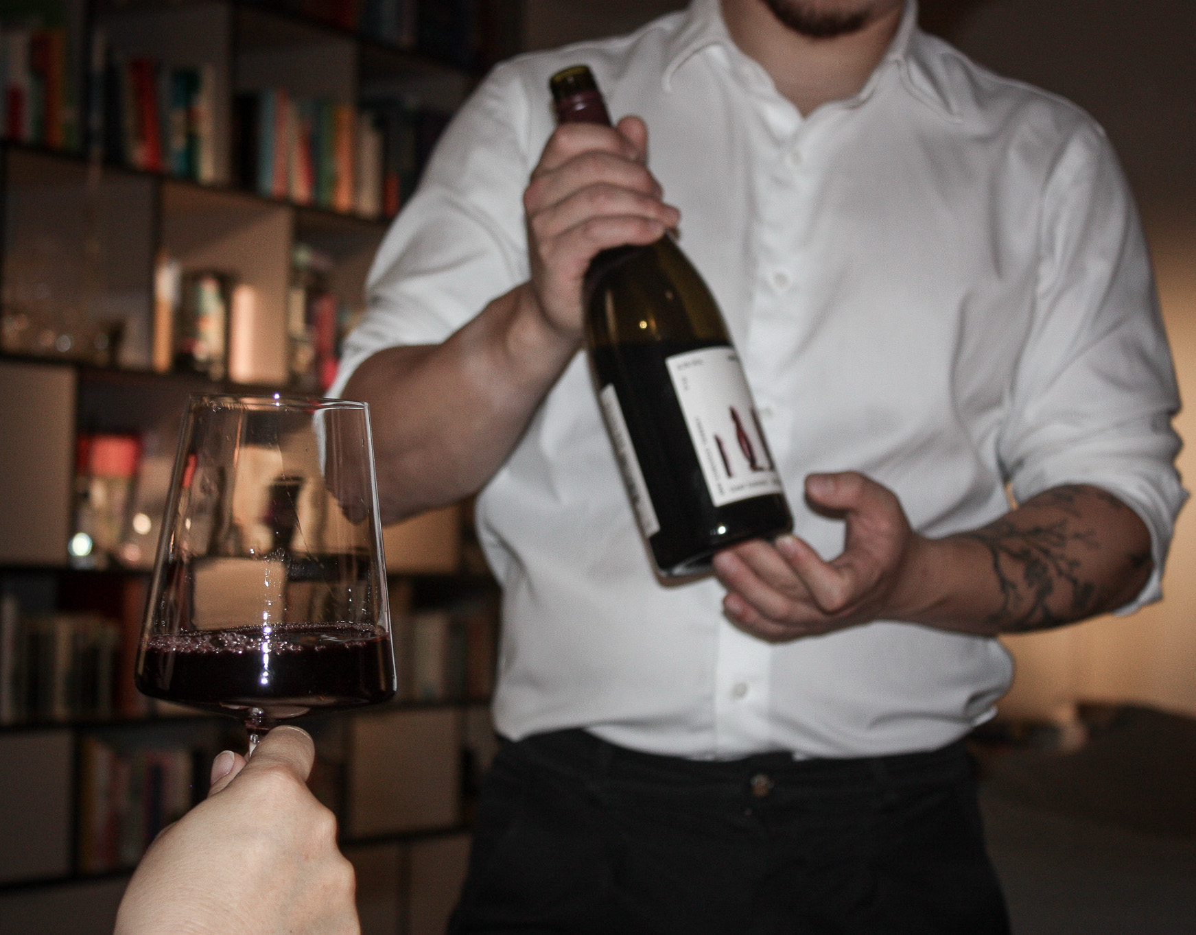 Sommelier holding red wine bottle and a wineglass filled with red wine