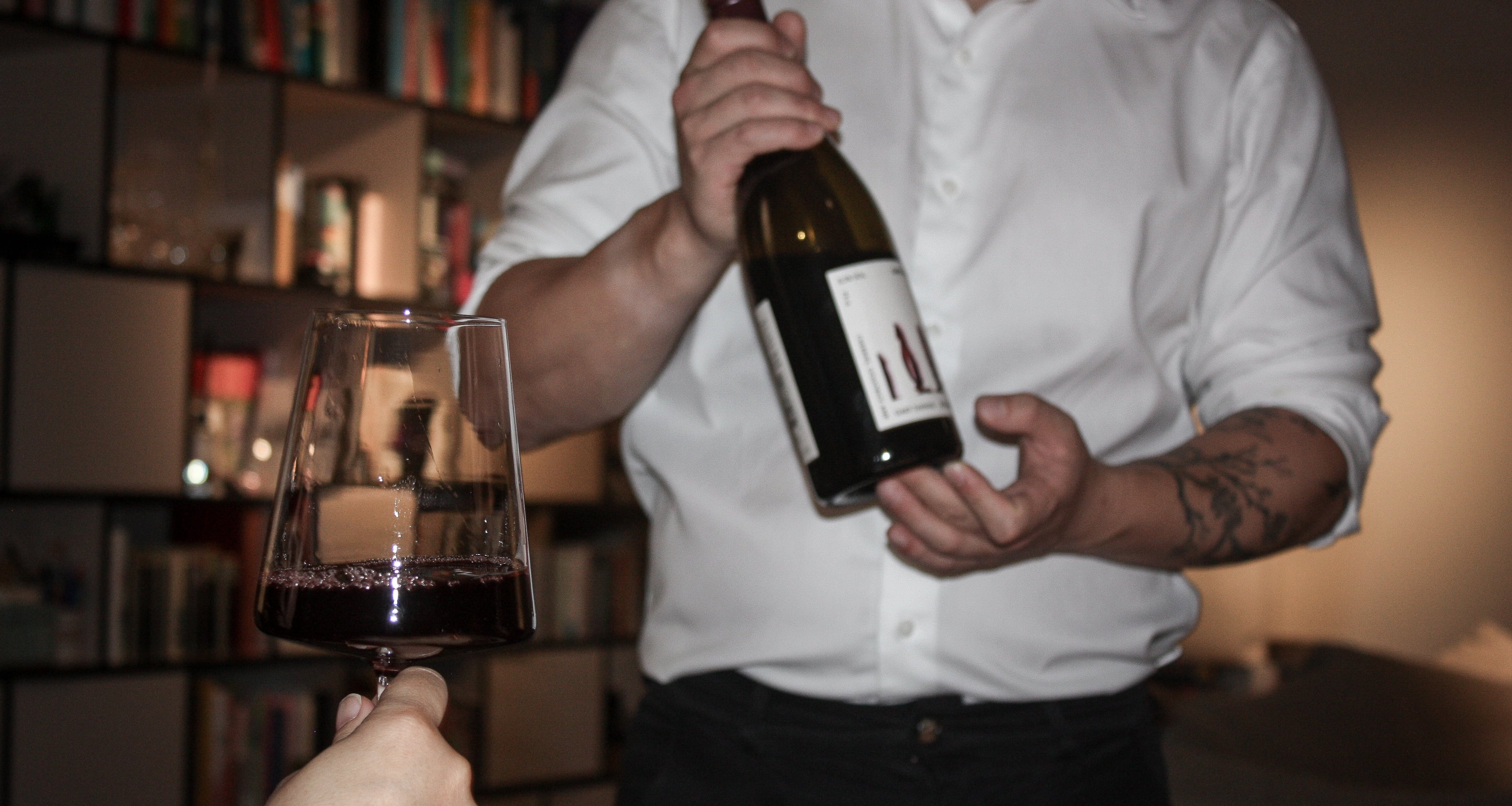 Sommelier holding wine bottle and a filled glass of red wine