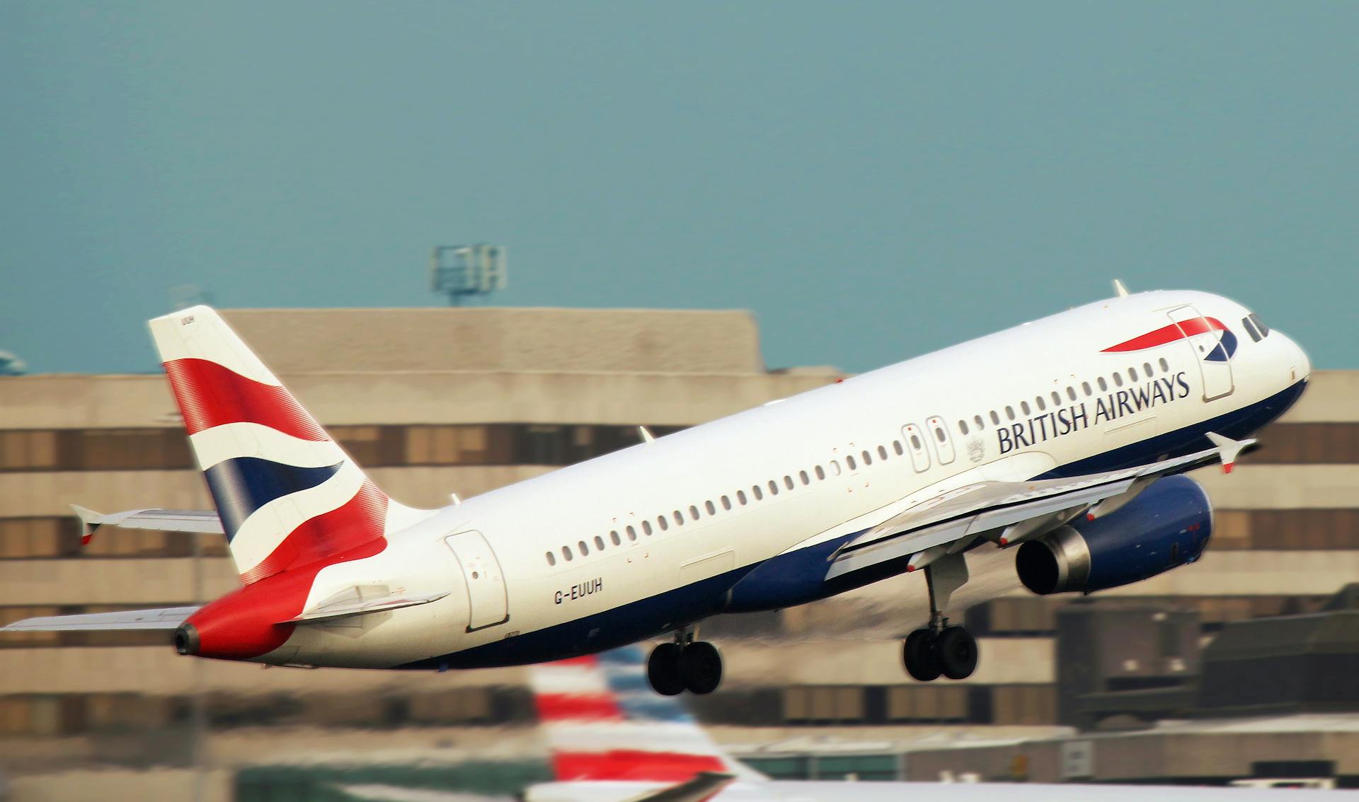 British Airways airplane taking off with buildings in the background.
