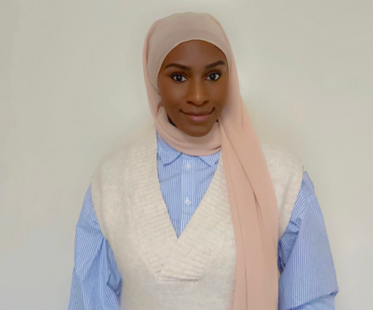 A woman wearing a blue shirt and a pink scarf.