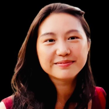 Portrait of a smiling young woman with long dark hair against a black background.