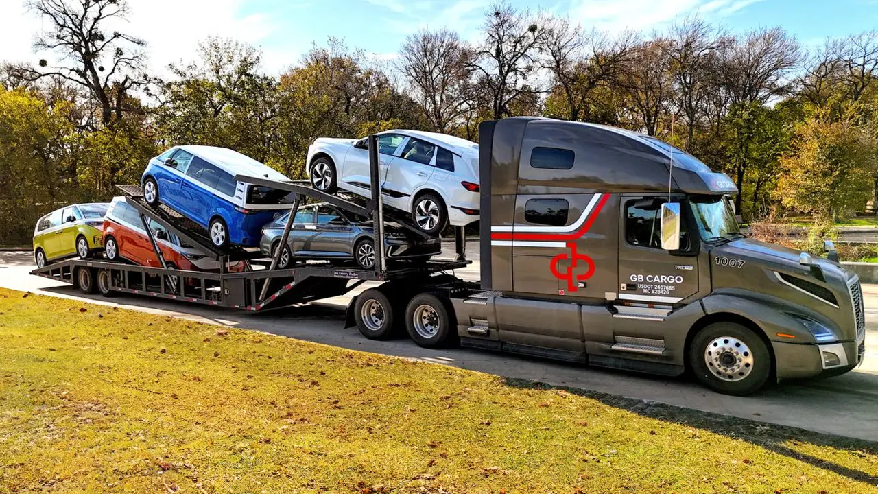 Electric Volkswagen vans loaded on a specialized car hauling truck