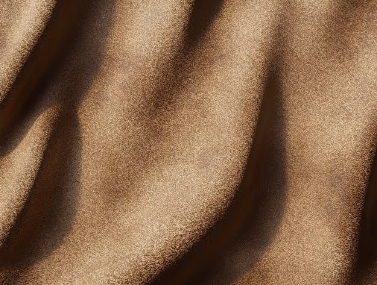 Close-up texture of brown leather with natural creases and subtle shadows.