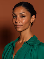 Portrait of a woman with dark hair pulled back, wearing a green blouse against a brown background.