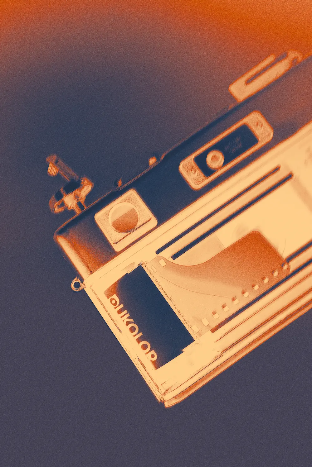 Nahaufnahme einer analogen Kamera mit eingelegte Dukolor-Filmrolle in warmen Orange- und Blautönen.