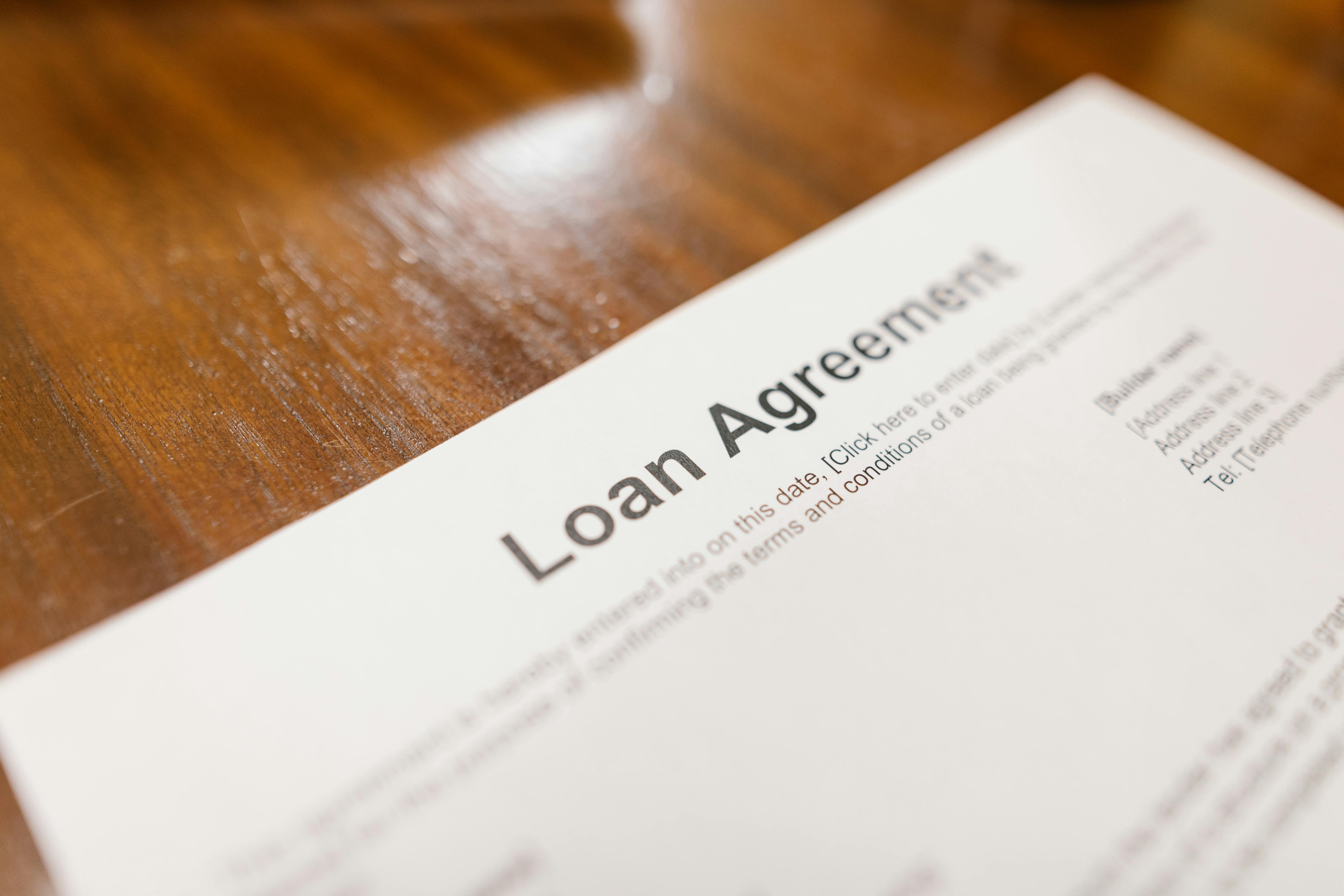 Partial view of a loan agreement document placed on a wooden surface.