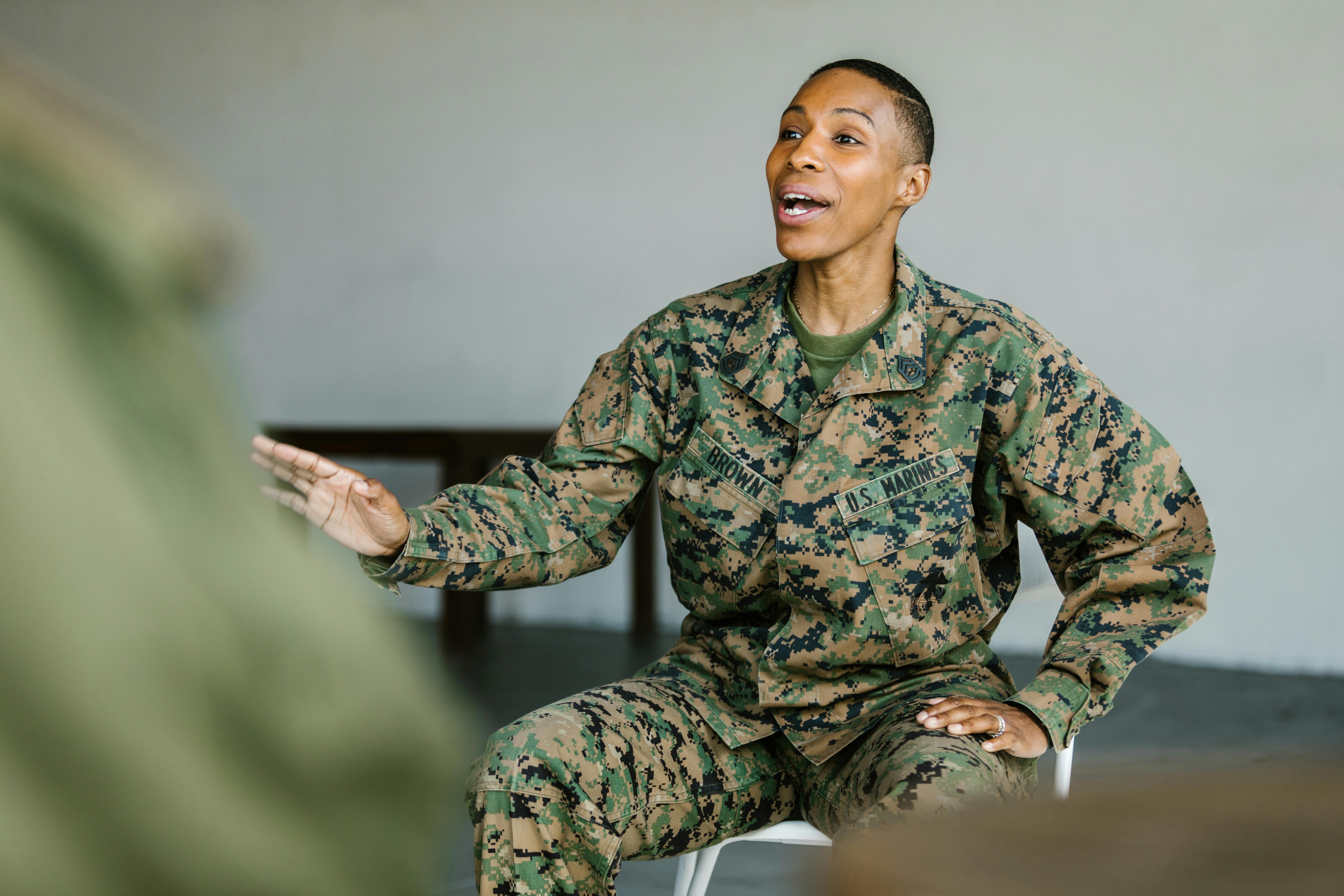 Female U.S. Marine in camouflage uniform sitting and gesturing while speaking.