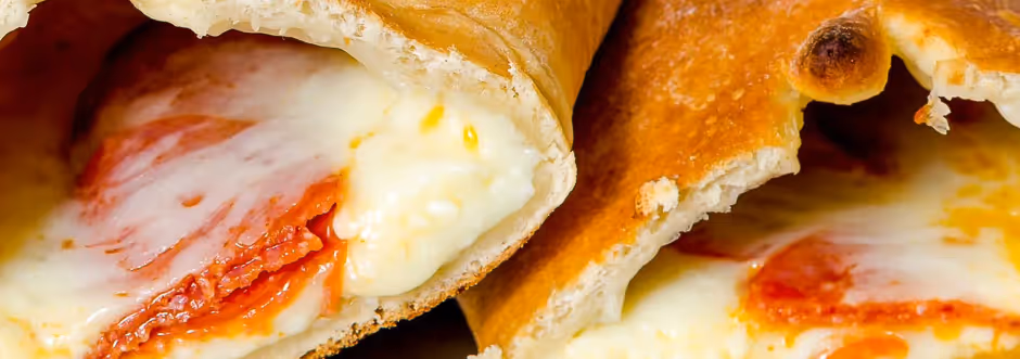 Close-up of calzones filled with melted cheese and pepperoni slices.