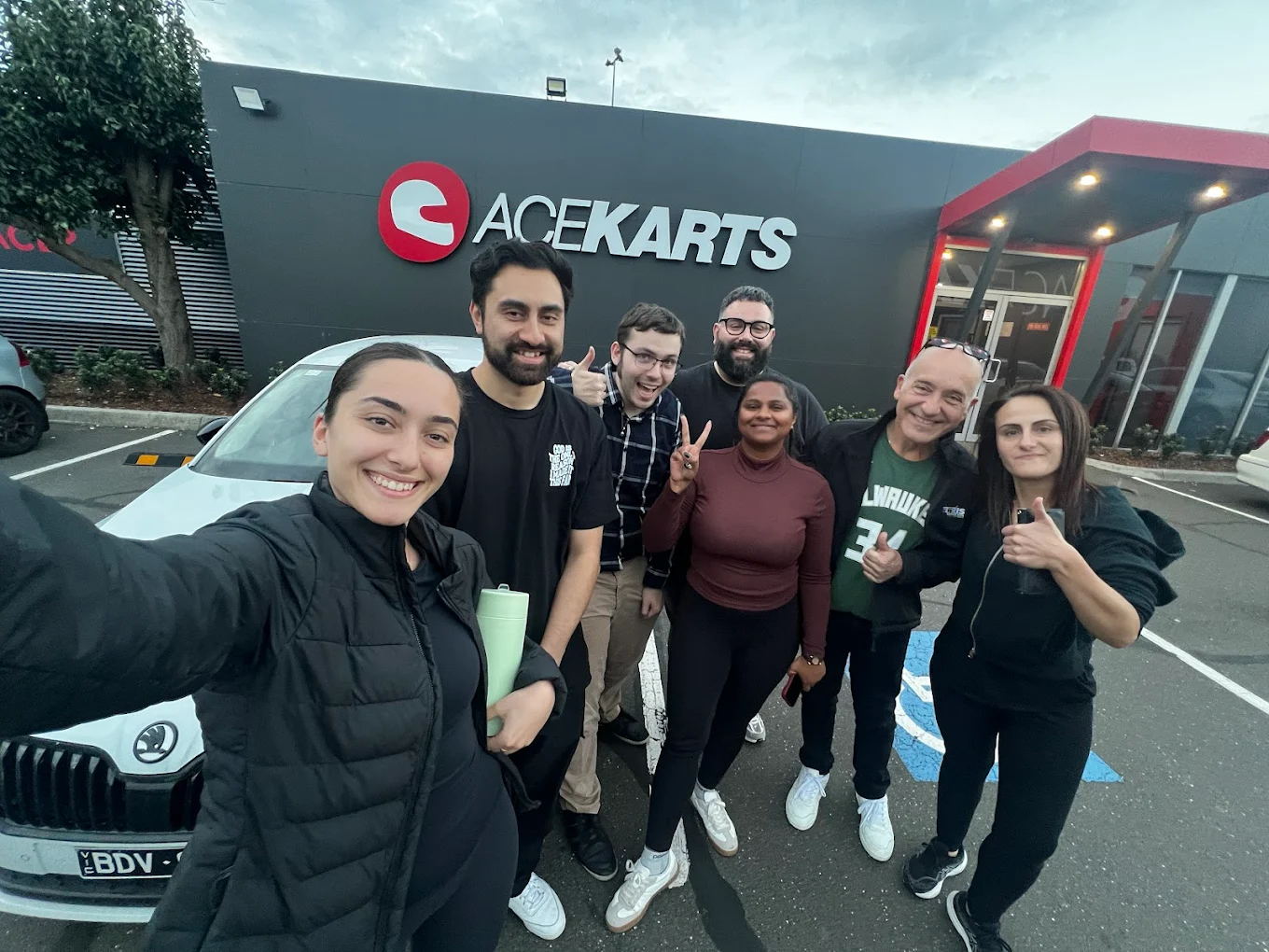 Two black and red go-karts on outdoor track viewed from low angle, person in purple shirt in kart number 12, person in black helmet in kart number 22
