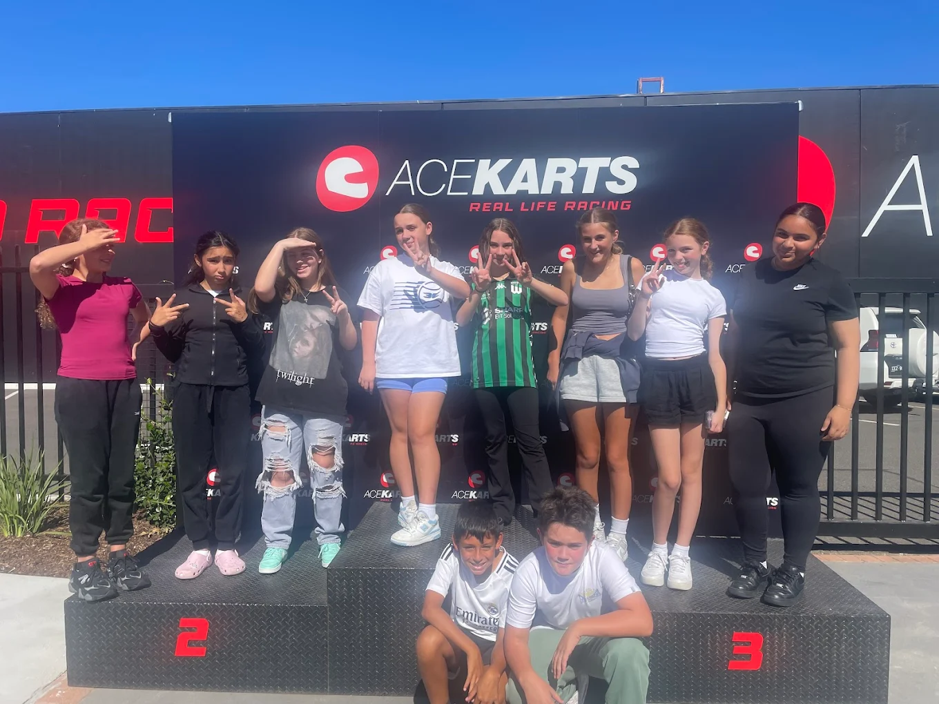Group of kids posing on the podium at the Ace Karts venue.