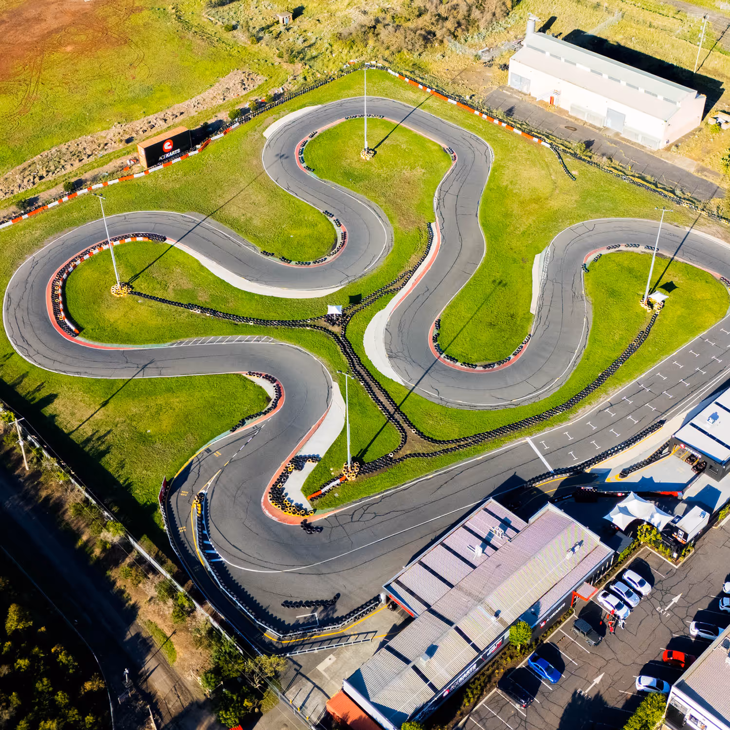 Go-karts racing on the Ace Karts outdoor track with safety barriers.