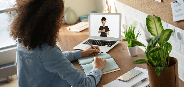 Person taking notes while watching a person signing help on a laptop screen