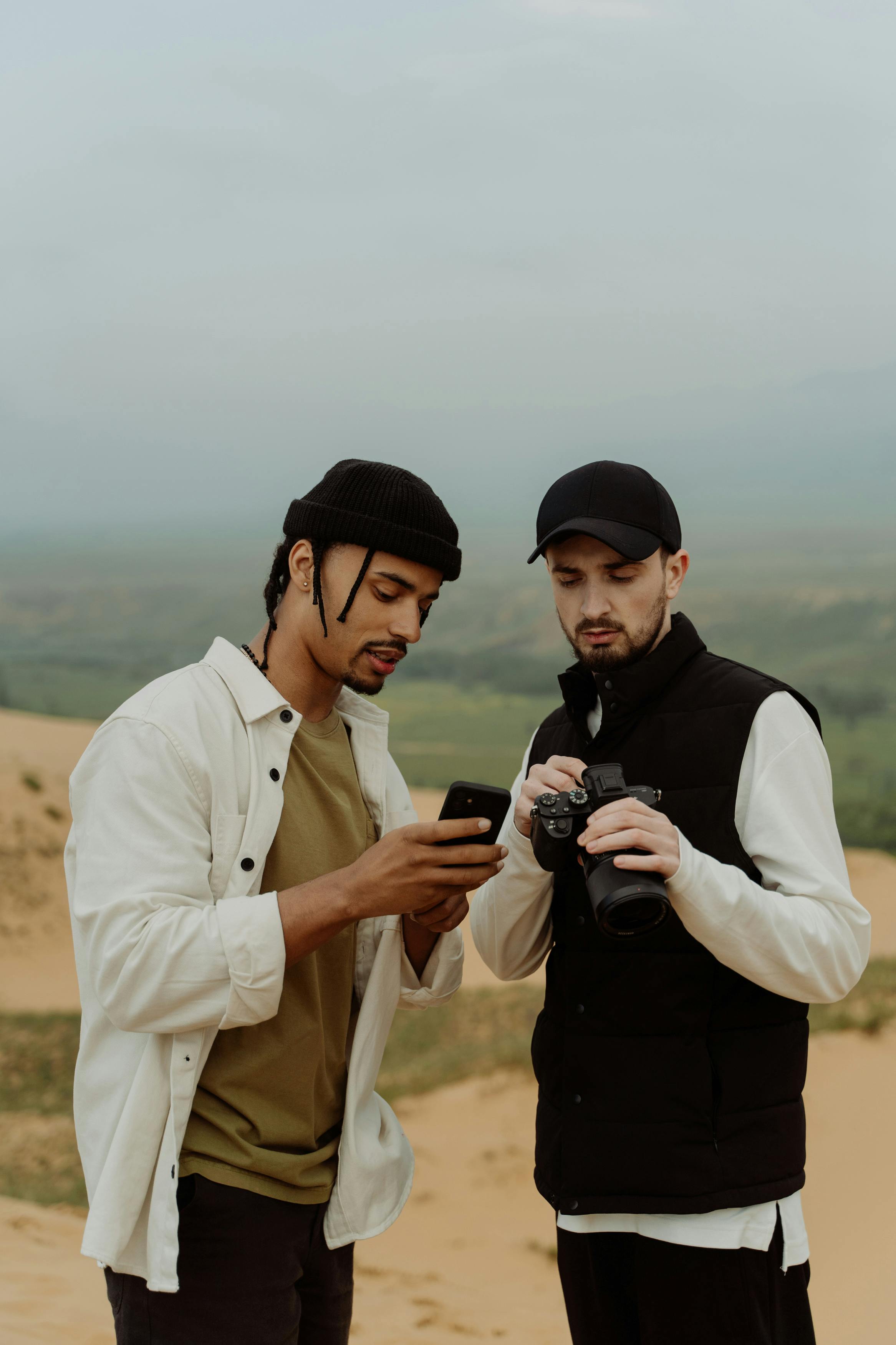 Two men standing outdoors, one man is looking at his smartphone