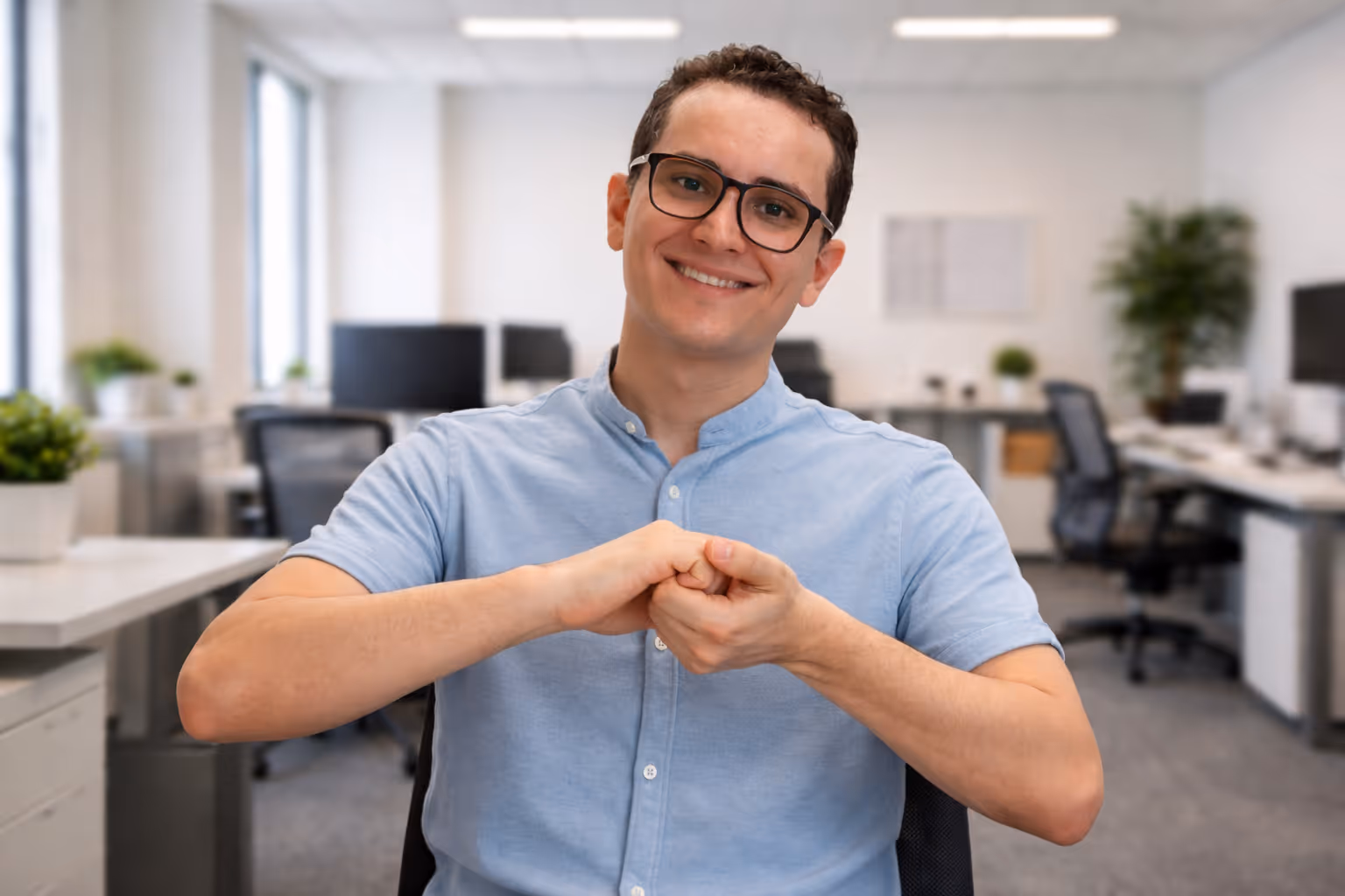 A man with glasses and light blue polo shirt in a office signing partnership.