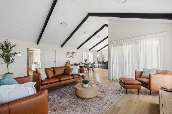 Living room with a cathedral ceiling and exposed dark beams meeting at a high central point